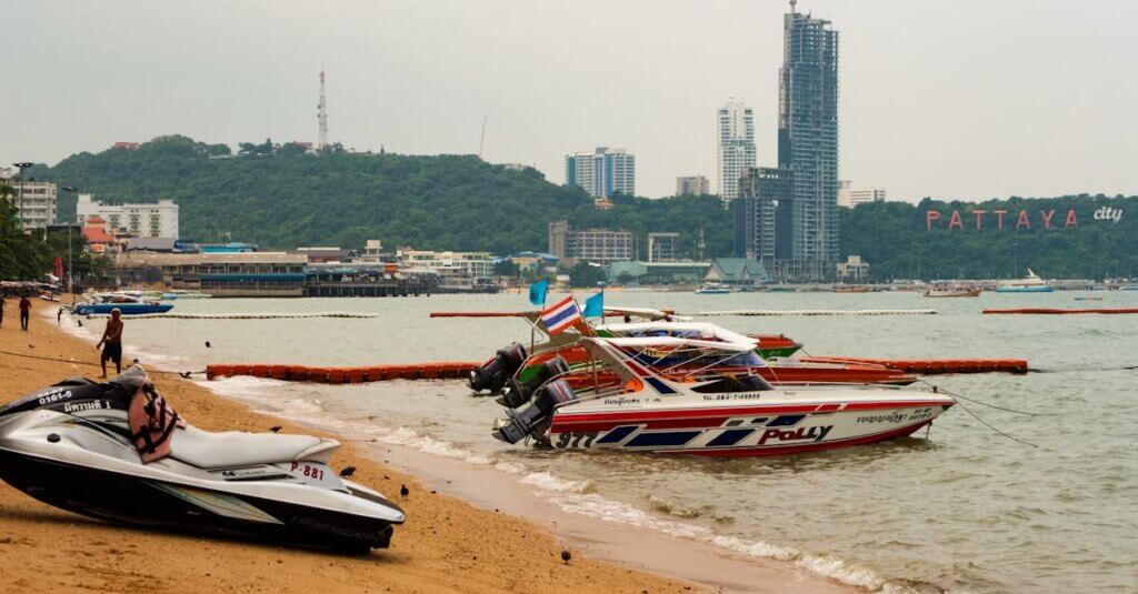Explore the bustling Pattaya beach in Thailand, showcasing lively speedboats and the iconic cityscape.